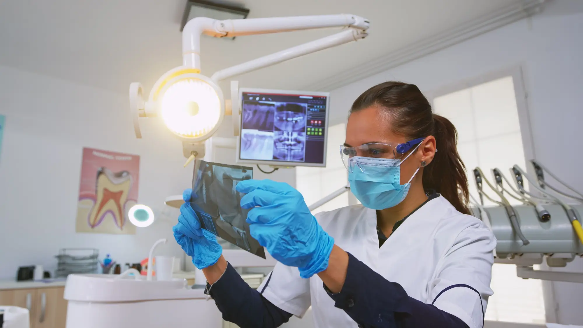 Dentist customizing light over the chair and analysing teeth x-ray Dentist customizing light over the chair and analysing teeth x-ray