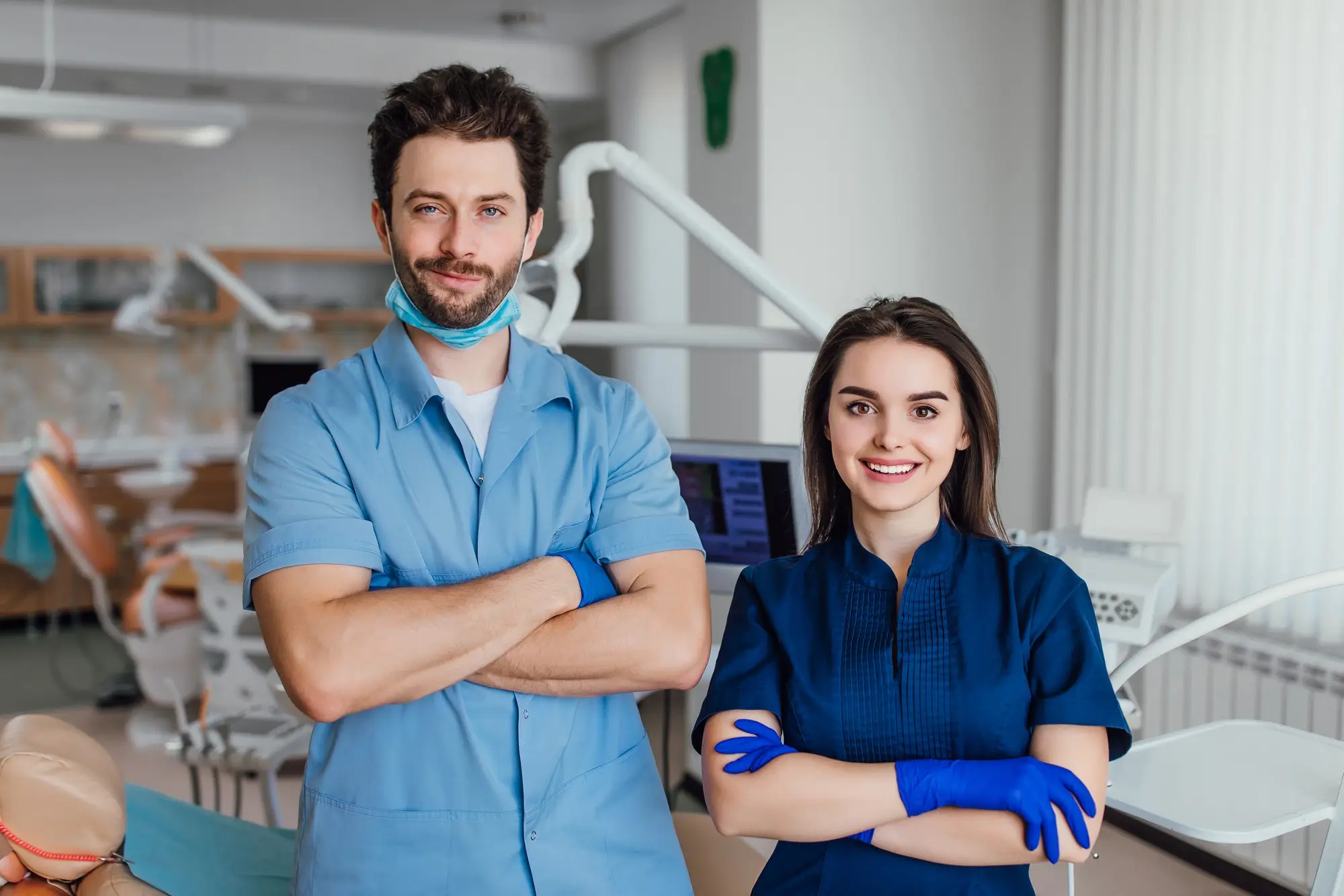 Portrait of smiling dentist standing with arms crossed with her colleague