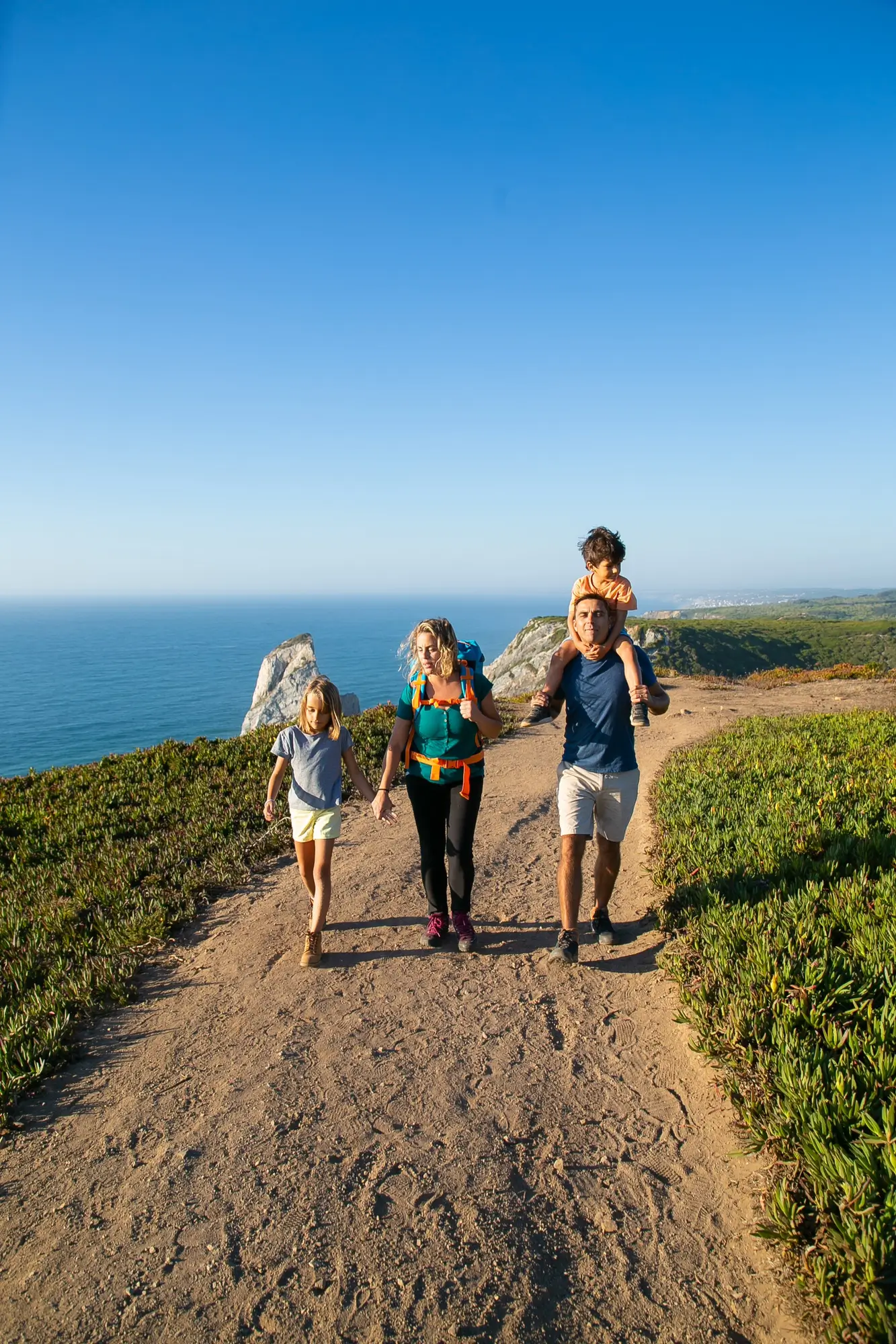 family couple and children hiking along seaside Active family couple and children hiking along seaside